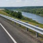Galvanized W-beam highway guardrail protecting a road beside a river and steep embankment