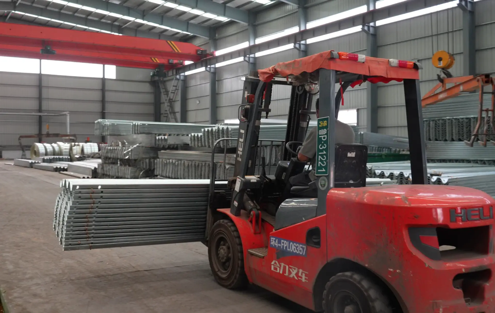 Forklift handling bundled galvanized guardrail beams inside the factory