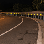 Nighttime highway curve with a guardrail and retroreflective delineators