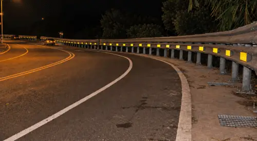 Nighttime highway curve with a guardrail and retroreflective delineators