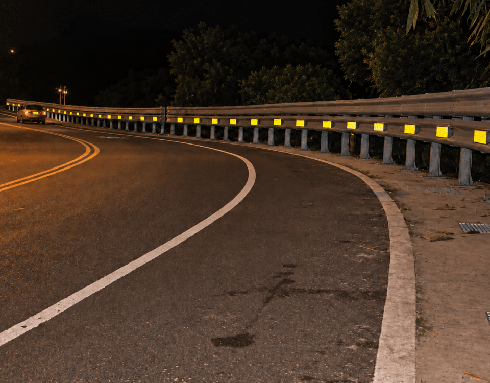 Nighttime highway curve with a guardrail and retroreflective delineators
