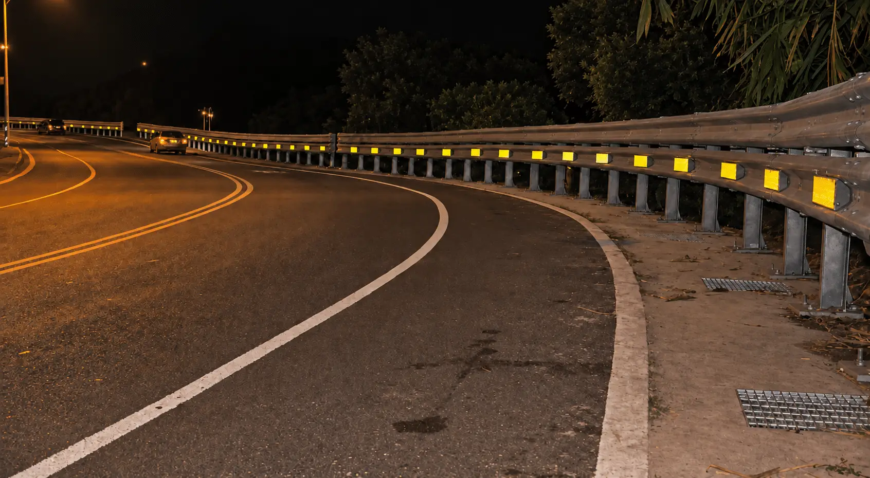 Nighttime highway curve with a guardrail and retroreflective delineators